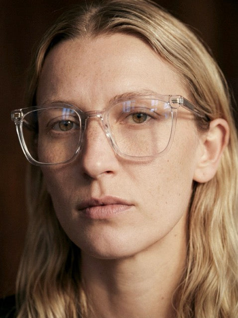 Frau mit blonden Haaren trägt eine transparente Einstärkenbrille Lucerne von Visiloox mit dünnen Premiumgläsern, Nahaufnahme im Editorial-Stil